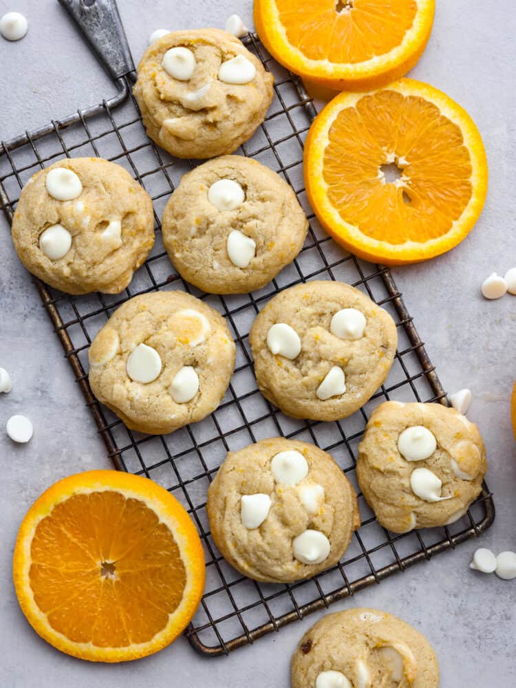 If you love orange creamsicles, you're going to LOVE these cookies! They're soft, buttery, and loaded with orange zest and white chocolate chips. Top-down view of 7 cookies on a cooling rack.