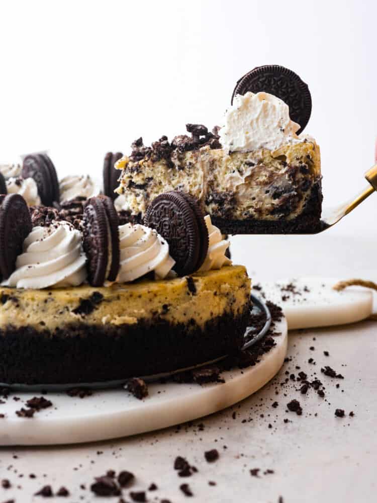 Let your teeth sink into the most delectable, creamy oreo cheesecake that you have ever had! Silky and smooth with the perfect bite-sized oreo bits in every single slice, you won't be able to stop raving about this cheesecake! A slice or oredo cheesecake being taken out with a gold pie server.