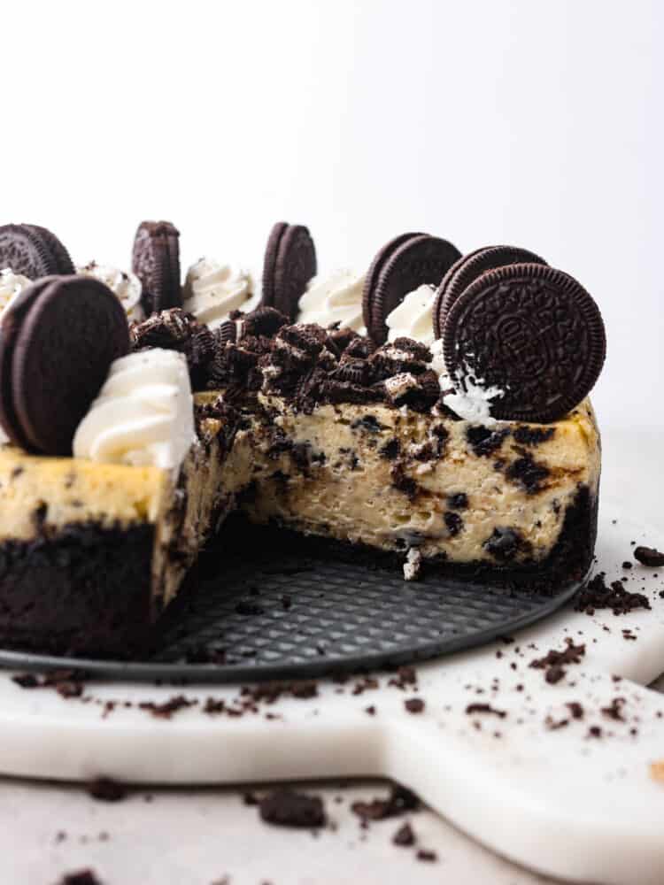 Let your teeth sink into the most delectable, creamy oreo cheesecake that you have ever had! Silky and smooth with the perfect bite-sized oreo bits in every single slice, you won't be able to stop raving about this cheesecake! An oreo cheesecake with one slice taken out so that you can see the inside.