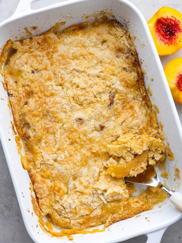 This 5-ingredient peach dump cake is a super easy dessert that is full of warm, cinnamony goodness. Top it off with a scoop of ice cream for a peachy, indulgent dessert the whole family will love. Top-down view of an entire peach dump cake with a scoop taken out of it.