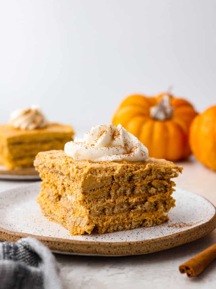 Layers of graham crackers and a creamy pumpkin filling make up this Pumpkin Pie Icebox Cake -- an easy no bake dessert for fall! Pumpkin icebox cake on a speckled plate.