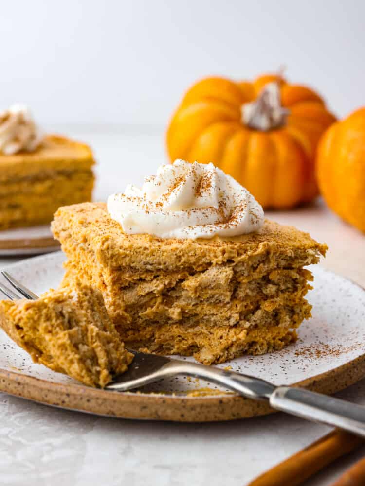Layers of graham crackers and a creamy pumpkin filling make up this Pumpkin Pie Icebox Cake -- an easy no bake dessert for fall! A slice of pumpkin icebox with a bite taken out with a fork.