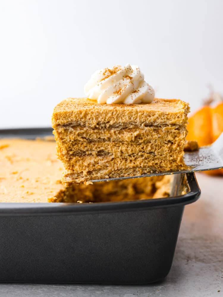Layers of graham crackers and a creamy pumpkin filling make up this Pumpkin Pie Icebox Cake -- an easy no bake dessert for fall! A slice of pumpkin icebox cake being served out of the baking dish.