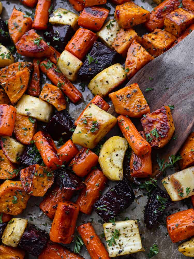 You have not had delicious vegetables until you have tried these roasted root vegetables! They have SO much flavor, and their texture is so tender that you will want to eat these with every meal! A close up of veggies being served with a wooden spoon.