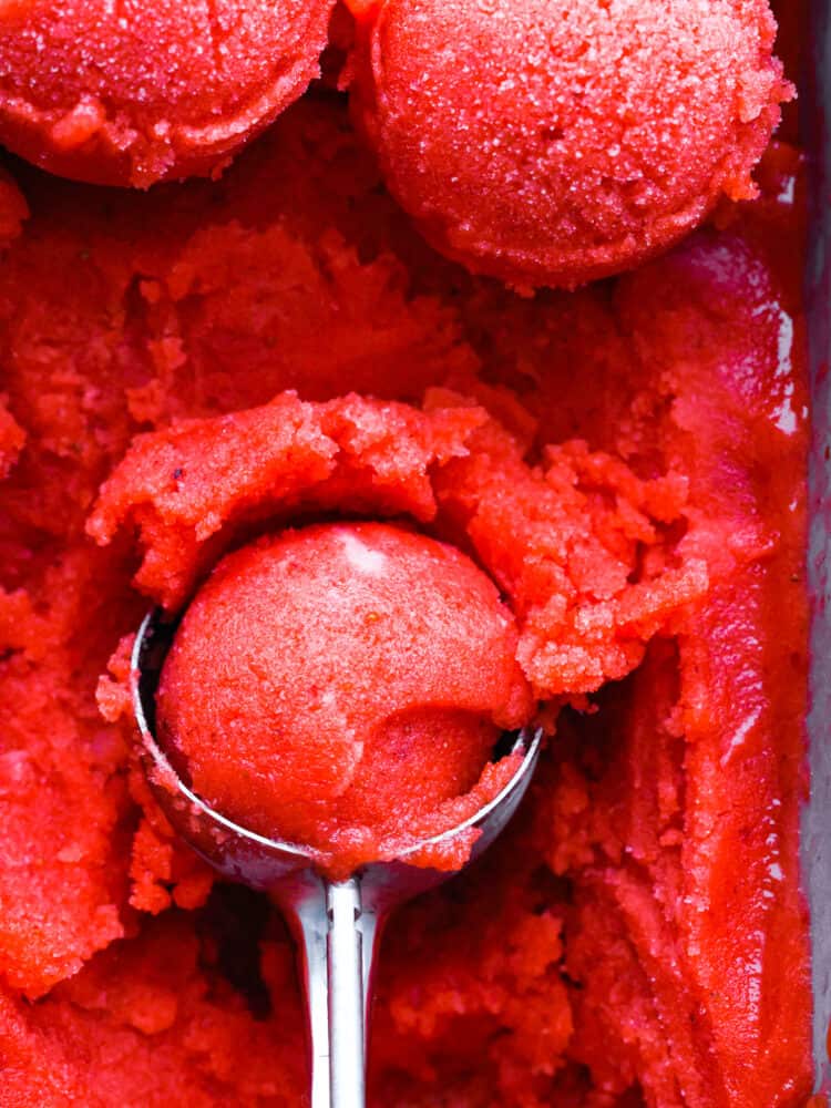 Get ready for the most refreshing homemade sorbet that you have ever had with this perfect recipe! Silky smooth, packed full of flavor, and a delightful dessert for any occasion, this will knock your socks off! A closup of the strawberry sorbet in a scoop.