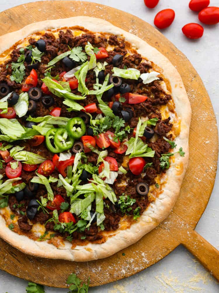 Two classic family favorites, pizza and tacos, come together in this easy weeknight meal that is destined to become a favorite in your home. Taco pizza is loaded with tasty seasoned beef, melty cheese, beans, and fresh veggies for a flavor combination you'll love! Top-down view of a whole taco pizza.