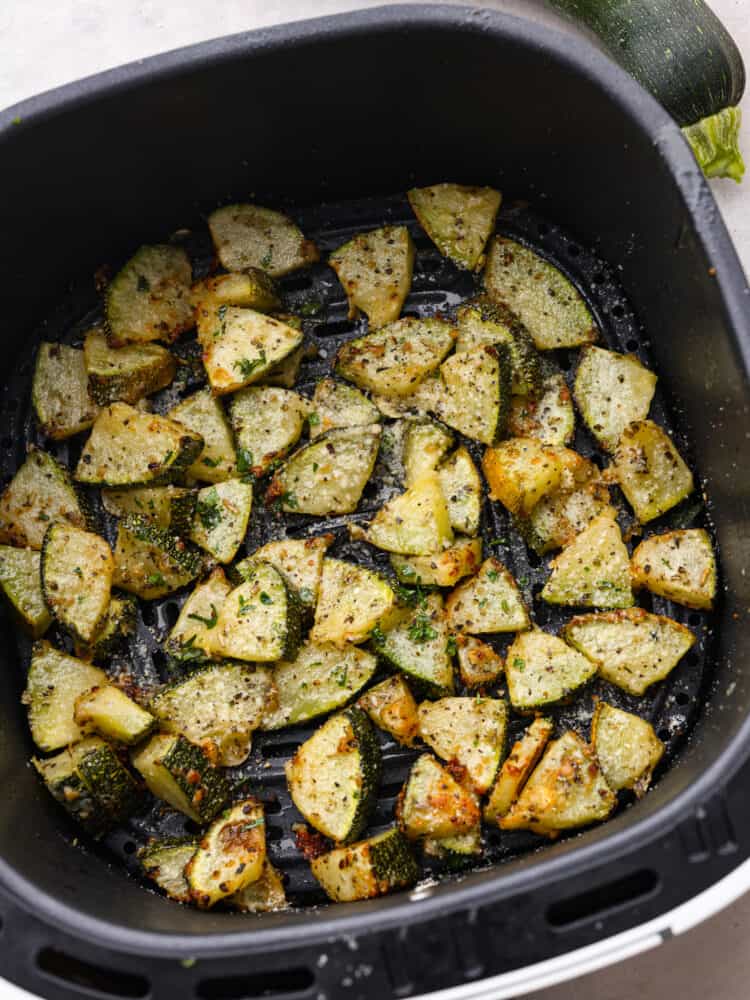 If you have never cooked air fryer zucchini, then you are in for the tastiest treat! It's perfectly seasoned with Italian seasonings and parmesan cheese and cooked to perfection! Cooked zucchini bites in an air fryer basket.