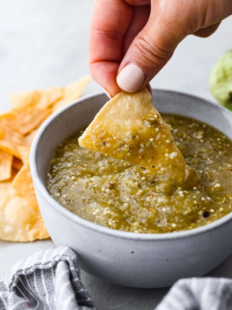 Fresh and delicious tomatillo salsa is the key to any successful Mexican meal! This is packed with so much flavor, and you will want to use it on everything! Dipping a tortilla chip into tomatillo salsa.