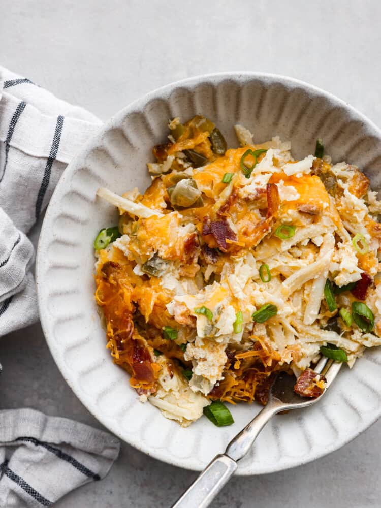 This overnight breakfast casserole is perfect for holidays when you have guests, or even just when you need a hearty breakfast that's made and ready to go! It's simple, easy, and totally delicious! A white bowl filled with breakfast casserole.
