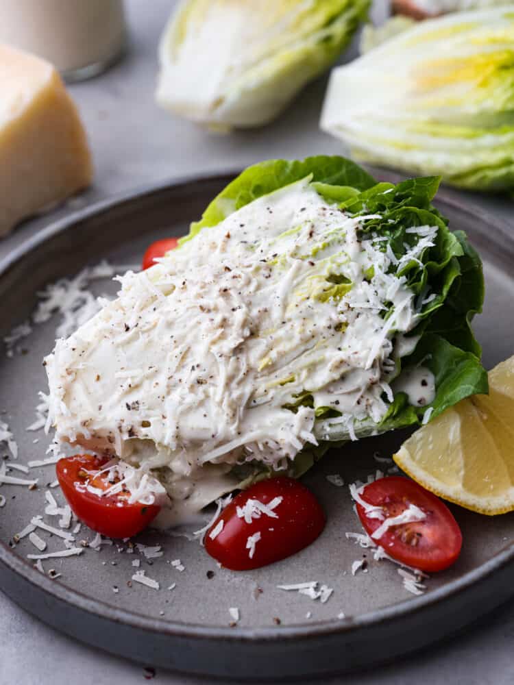 This caesar wedge salad is a twist on a classic starter and it's filled with delicious and fresh flavors! It's perfect for serving with every meal and your whole family will love it! A caesar wedge salad with dressing and cheese on top sitting on a plate