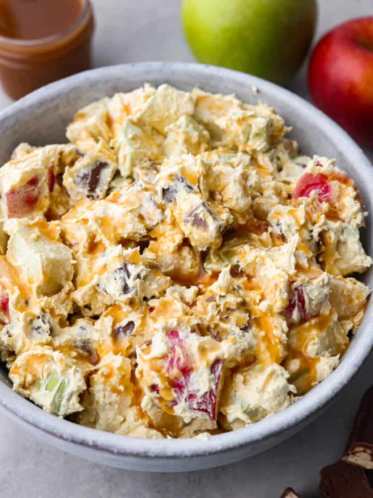 Snickers salad is perfect for any potluck! It's a mixture of snickers bites and apples, all covered in a vanilla cool whip and topped with chocolate and caramel sauce. This perfectly sweet and salty salad is so delicious and surprisingly easy to make! Snickers salad in a bowl.