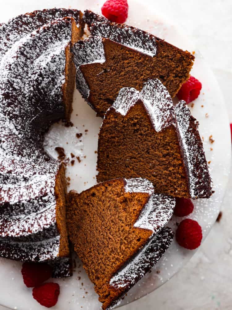 Get ready to eat the best dessert that you will have all year long! This chocolate pound cake tastes as good as it looks, and it is the perfect dessert for any occasion! The top view of a chocolate pound cake on a cake stand with a few pieces sliced.