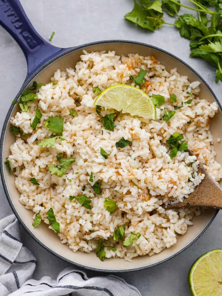 This cilantro lime rice makes the perfect side dish to complement any Mexican meal! It is packed with flavor, and the best part is... it takes less than 30 minutes to make! A pan of cilantro lime rice with a lime wedge on top.