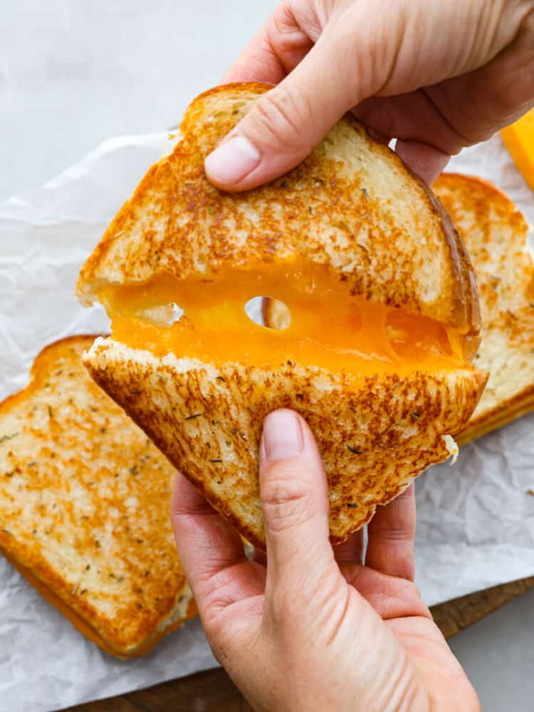 You will never cook another grilled cheese sandwich again after you try this one! It's deliciously cheesy on the inside, and once you sink your teeth into that crispy outside, it is absolute perfection! A grilled cheese sandwich cut in half and being pulled apart.