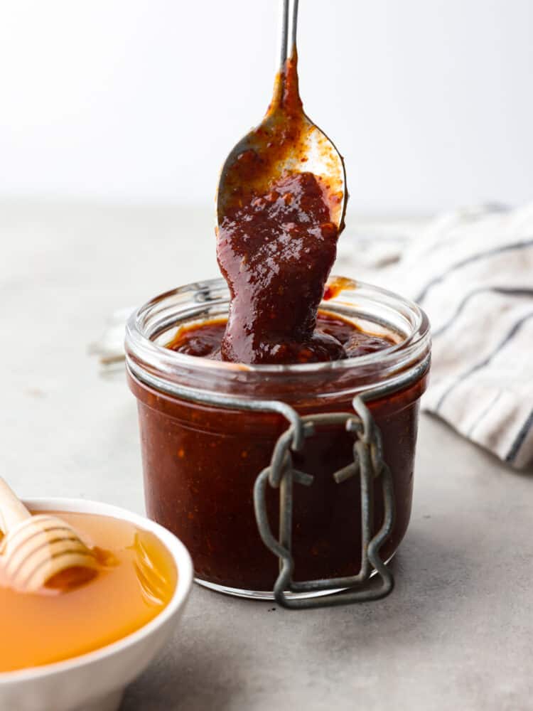 This honey chipotle sauce is packed with so much flavor you will want to put it on everything! The blended spices will elevate any meal and have all of your guests asking for the recipe! A jar of honey chipotle sauce with a spoon scooping some out.