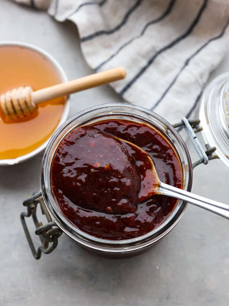This honey chipotle sauce is packed with so much flavor you will want to put it on everything! The blended spices will elevate any meal and have all of your guests asking for the recipe! The top view of a jar of honey chipotle sauce with a silver spoon in it.