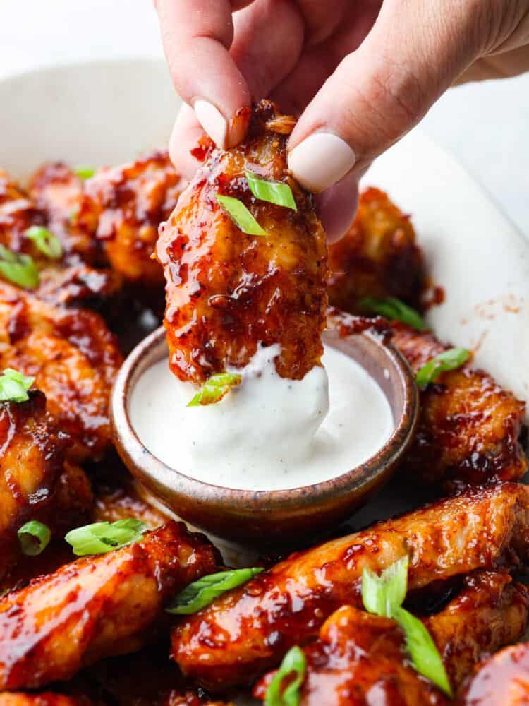 Honey chipotle wings are sweet and spicy and pack a punch of flavor! You will definitely want to serve them as an appetizer on any game day, and they will be the hit of the party! A close up of a wing being dipped into ranch dressing.