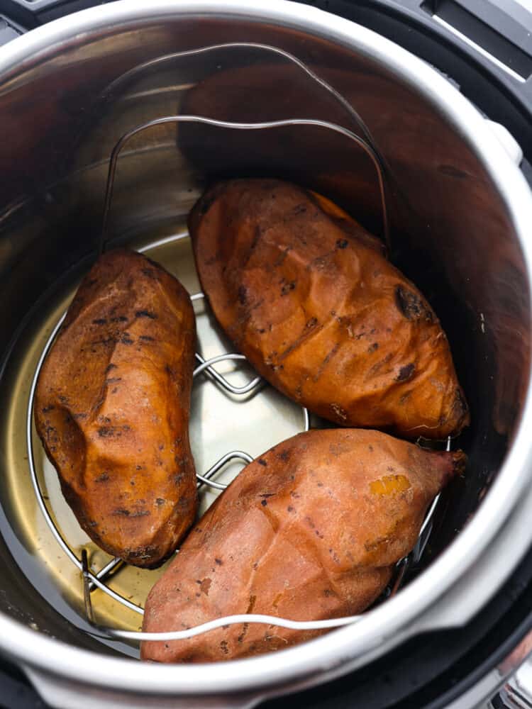 Using an Instant Pot to cook your sweet potatoes is the best! They turn out perfectly sweet, creamy, and soft in half the time it takes to bake them! 3 cooked sweet potatoes in the base of an Instant Pot.