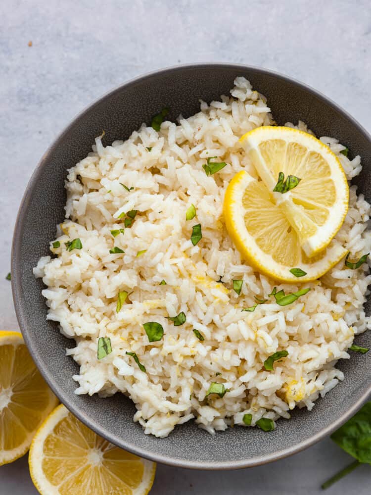 This zesty lemon rice is the perfect summer side dish! It's creamy, savory, and packed with bright citrus flavor! Serve it with your favorite fish or meat dishes for a crave-worthy meal. Rice in a black bowl, ready to be eaten.