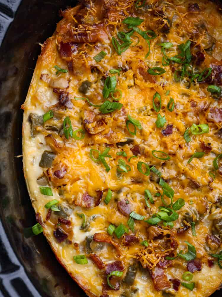 This overnight breakfast casserole is perfect for holidays when you have guests, or even just when you need a hearty breakfast that's made and ready to go! It's simple, easy, and totally delicious! A close up of cooked overnight breakfast casserole in the crockpot.