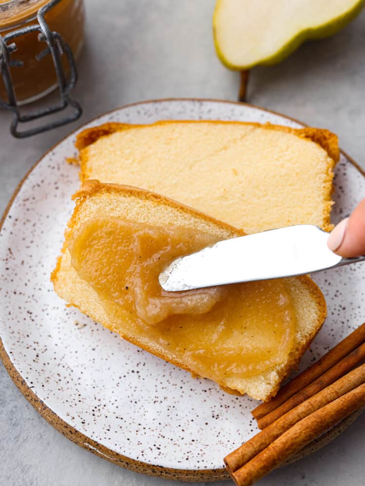 Sweetened with honey and warm spice, this homemade pear butter is a fall staple you'll want to put on everything! It's great for canning and storing to enjoy with all of your favorite baked goods year-round. Spreading pear butter on two slices of pound cake.