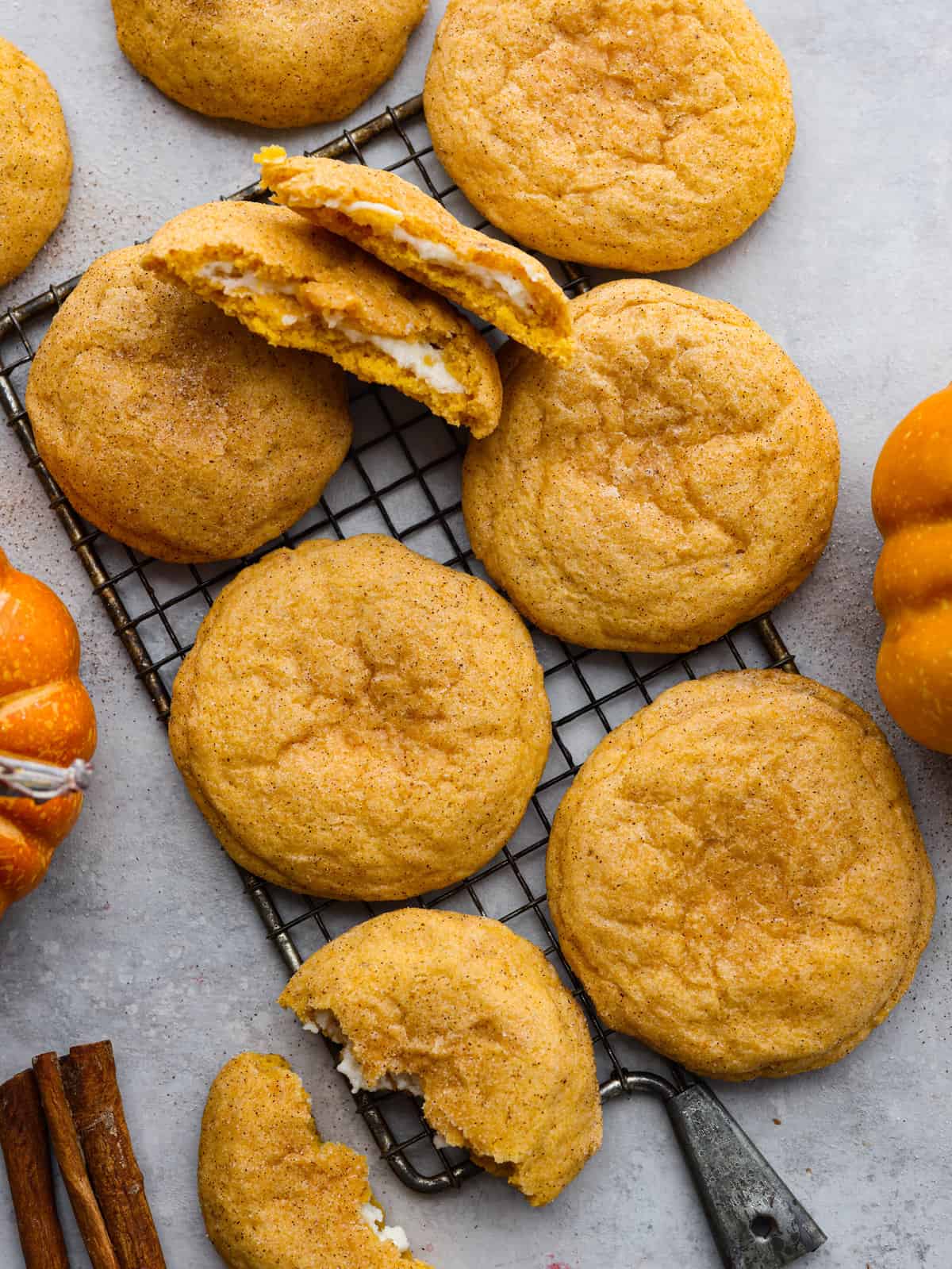 Pumpkin cheesecake snickerdoodles are a fresh take on a classic cookie! Delightfully soft and filled with tangy cream cheese, these cookies will be sure to get a "WOW!" from your friends and family! Pumpkin cheesecake snickerdoodles on a cooling rack.