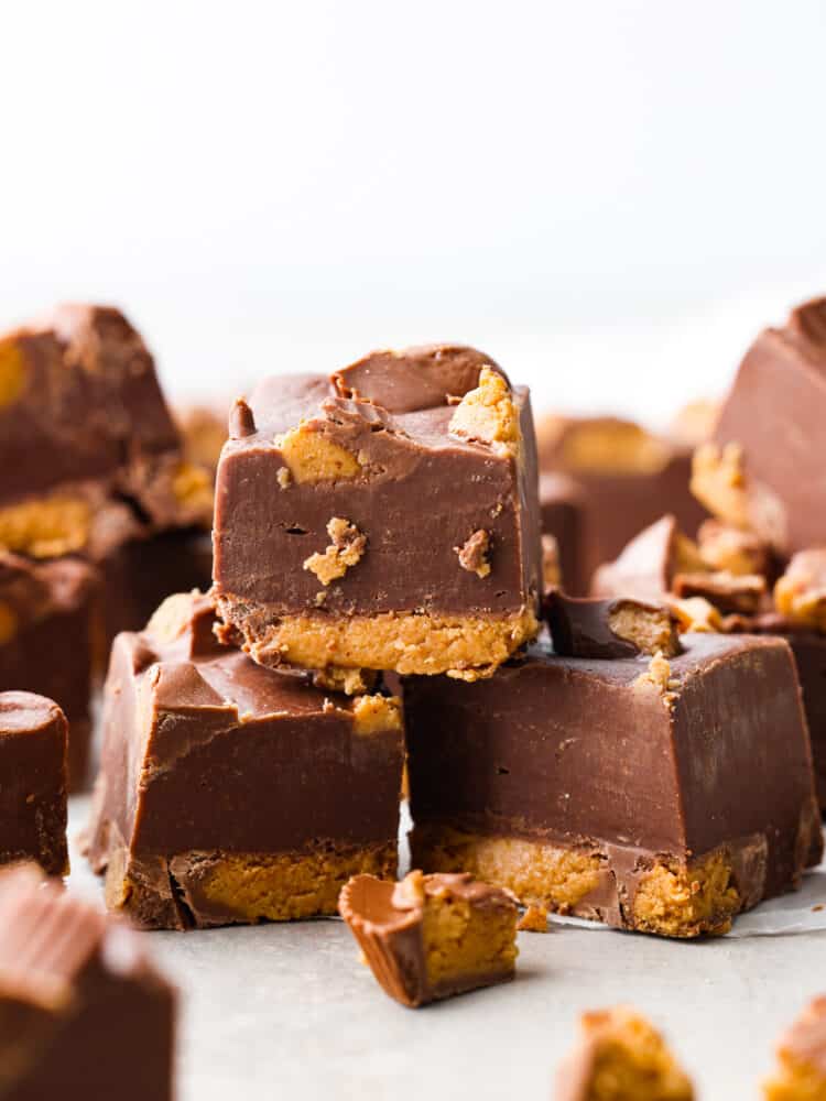 An easy 3 ingredient no-bake fudge that has Reese's Peanut Butter Cups inside. Reeseโs fudge is creamy and delicious and only takes 20 minutes to throw together! It will have the whole family wanting more. A stack of 3 pieces of fudge.