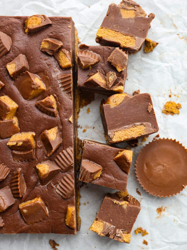 An easy 3 ingredient no-bake fudge that has Reese's Peanut Butter Cups inside. Reeseโs fudge is creamy and delicious and only takes 20 minutes to throw together! It will have the whole family wanting more. Top-down view of Reese's fudge cut into slices.