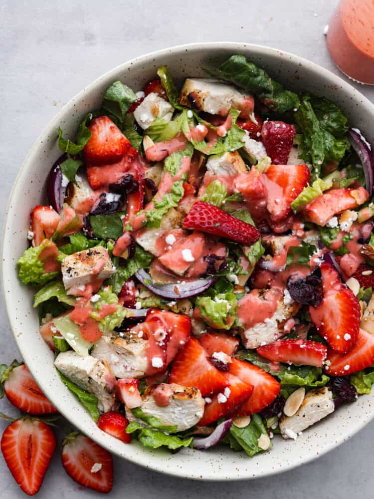 This strawberry vinaigrette is a delicious combination of sweet and tart all at the same time. It's the perfect way to brighten up any meal and it's so flavorful that you'll find yourself putting it on everything! The top view of a salad with strawberry vinaigrette drizzled on top.