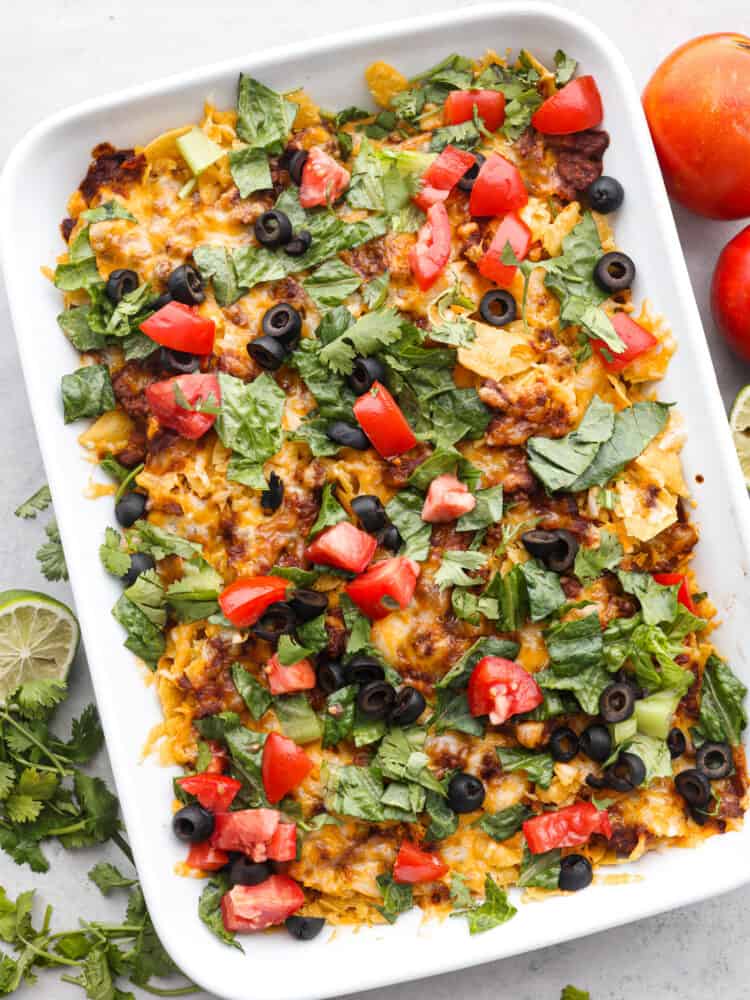 Easy taco casserole is beef, cheese, and tortilla chips layered up and loaded with rich flavor throughout. It is an easy-to-make, crowd-pleasing dinner that will be a hit with everyone! The top view of taco casserole in a 9x13 baking dish.