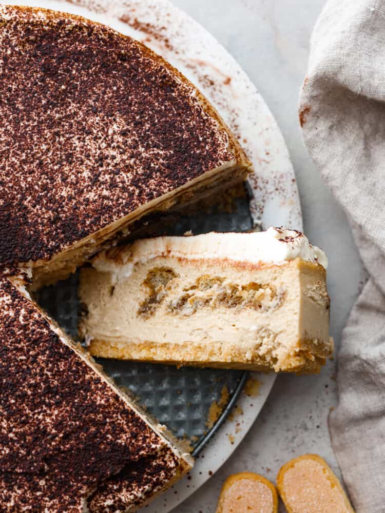 This decadent and delicious tiramisu cheesecake is creamy and will melt in your mouth with every bite. Trust me when I tell you that you will want to make this dessert every time you have guests! The topview of a tiramisu cheesecake with one slice laying on its side.