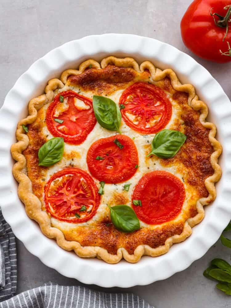 Filled with creamy mayonnaise and cheddar cheese mixture layered in between thick sliced of summer tomatoes makes this The Best Tomato Pie. There's no better way to close out summer than making this delicious southern recipe. The top view of a tomato pie in a white pie pan.