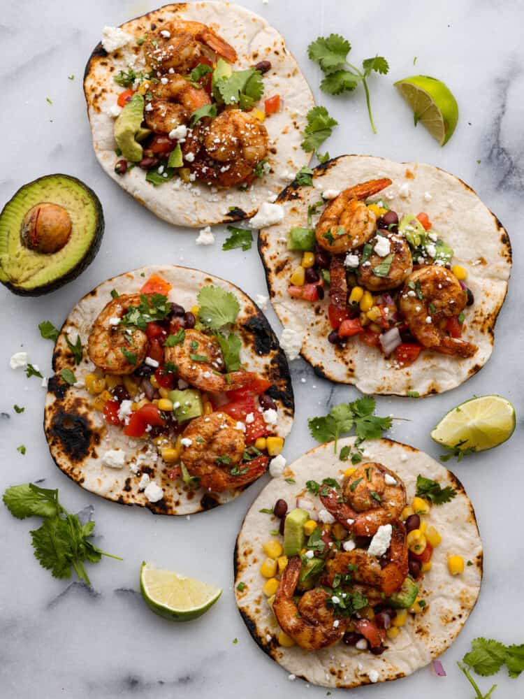 Blackened Cajun Shrimp Tacos with Avocado Salsa are made with so many fresh ingredients and the blackened cajun shrimp takes it to the next level with flavor! These are some healthy and delicious tacos you have got to try!ย 4 assembled blackened Cajun shrimp tacos with avocado salsa.
