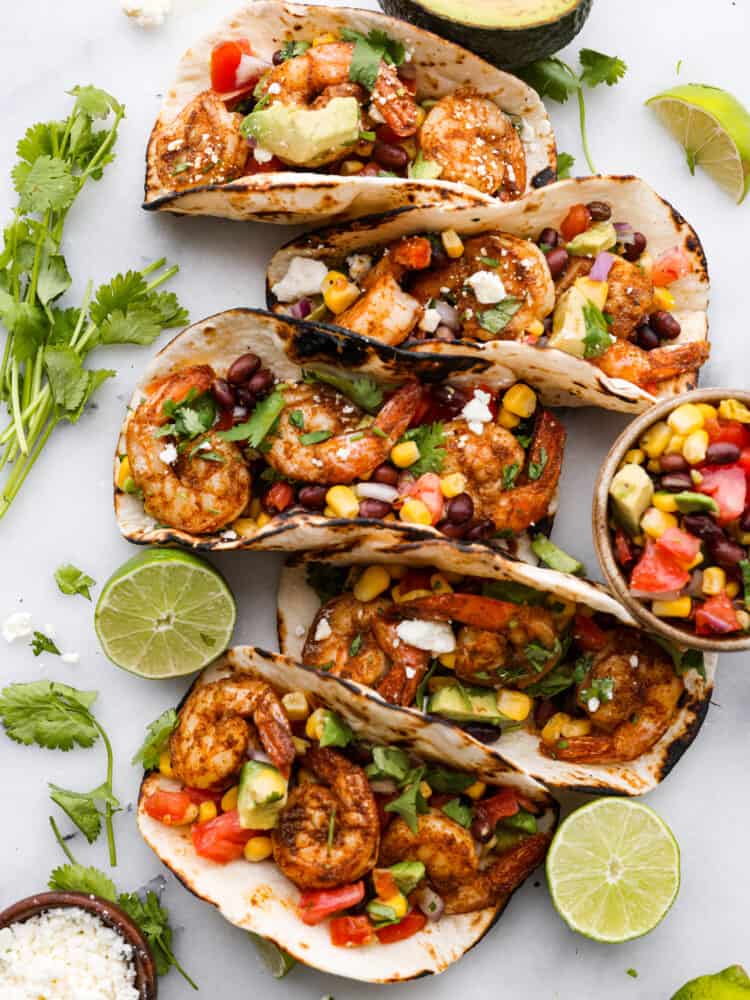 Blackened Cajun Shrimp Tacos with Avocado Salsa are made with so many fresh ingredients and the blackened cajun shrimp takes it to the next level with flavor! These are some healthy and delicious tacos you have got to try!ย The top view of 5 blackened cajun shrimp tacos.