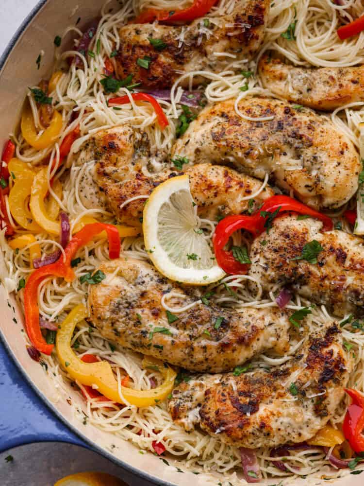 Crispy breaded chicken, angel hair pasta, and an amazing lemon garlic butter sauce combine to make this knockout chicken scampi. It's light, flavorful, and ready in less than 30 minutes! Closeup of chicken scampi in a white and blue skillet.