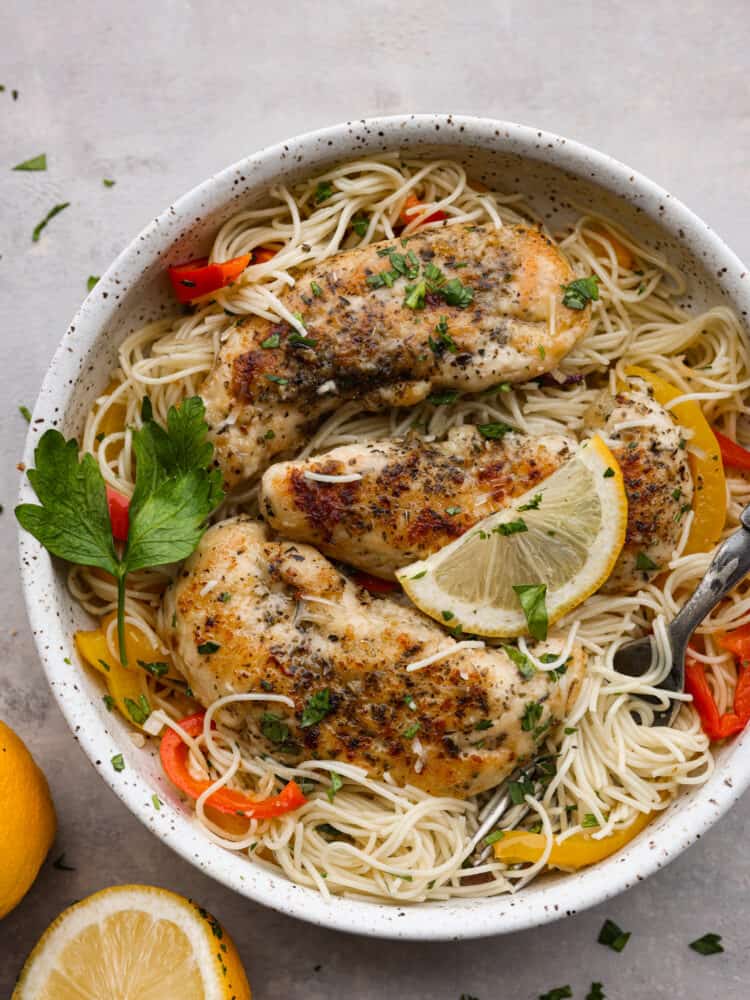 Crispy breaded chicken, angel hair pasta, and an amazing lemon garlic butter sauce combine to make this knockout chicken scampi. It's light, flavorful, and ready in less than 30 minutes! Chicken scampi served with angel hair pasta in a white stoneware bowl, garnished with fresh parsley and a lemon slice.