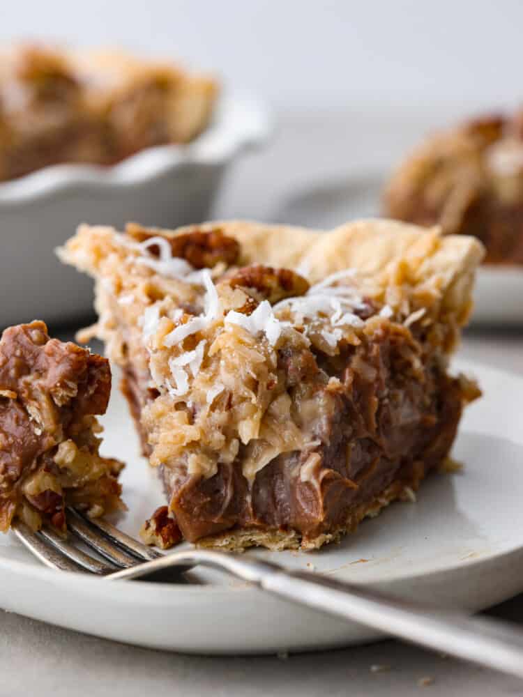 This decadent dessert is everything you love about German chocolate cake in one easy-to-make pie! Layers of chocolate custard, perfectly sweet shredded coconut, and salted pecans all in a golden, flaky crust. It's the perfect addition to your Thanksgiving table! Closeup of a slice of German chocolate pie with a bite taken out of it.