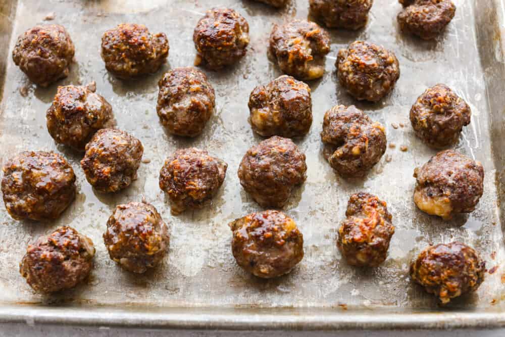 Whether you're making subs or spaghetti, these classic oven-baked meatballs are perfect for all of your favorite recipes. They're perfectly juicy and flavored with delicious seasonings and parmesan cheese! A pan filled with uncooked meatballs.