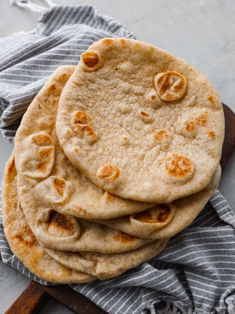 This homemade pita bread is soft, fluffy, and full of authentic flavor! Yes, you can buy pita bread at the store, but a freshly baked pita tastes so much better and will make your home smell absolutely delicious. Everyone will want to know what you are making! The top view of a stack of pita bread.