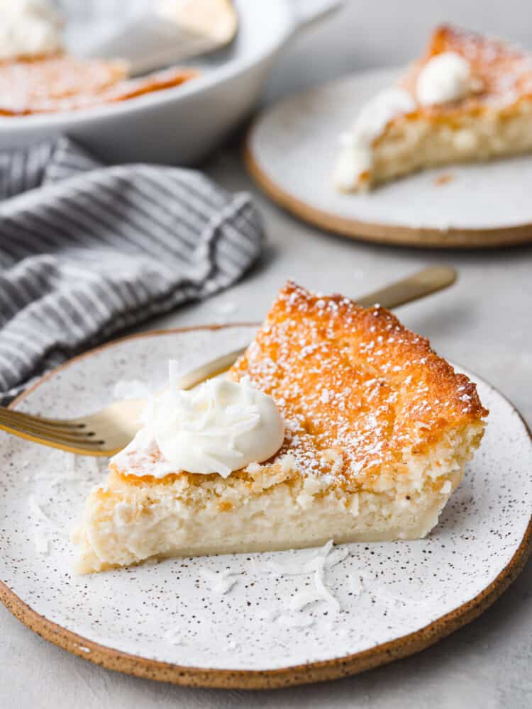 Don't be fooled by the name, this impossible pie is one of the easiest pies you'll ever make! Called "impossible" because it magically forms its own crust, you can have this pie ready for the oven in just 7 minutes. This pie is a classic for a reason- the creamy custard filling and crunchy topping are irresistible! A slice of impossible pie topped with whipped cream on a stoneware plate.