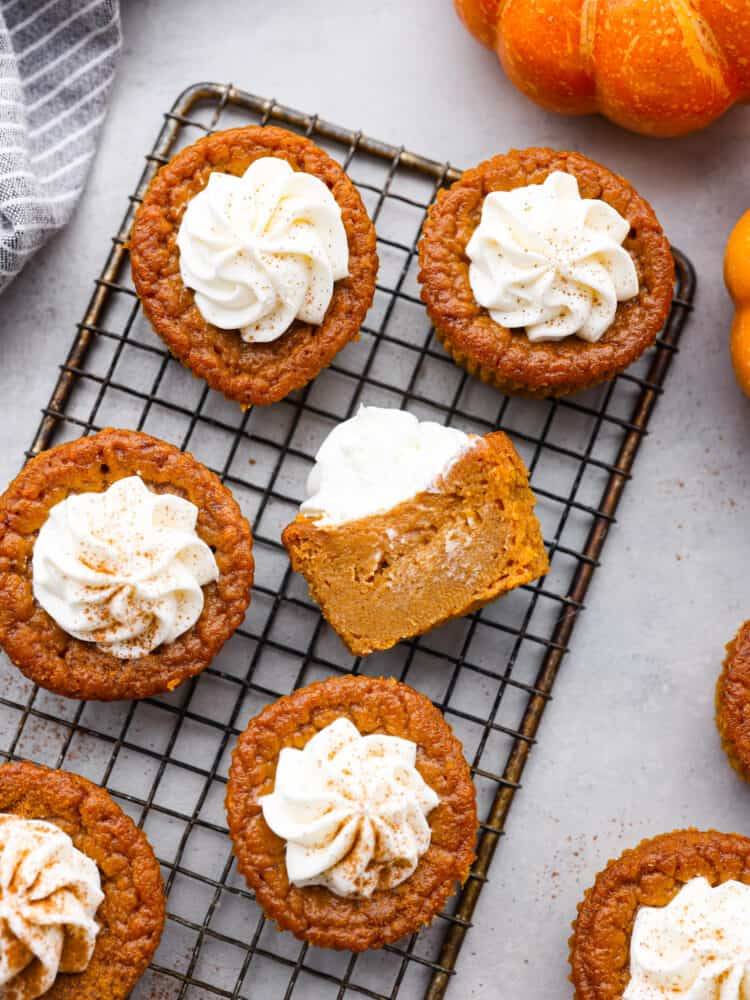 These moist and tender pumpkin pie cupcakes are all of the things you love about pumpkin pie, just bite-sized! Topped with amazing cream cheese whipping cream, these will be the BEST cupcakes you'll ever eat!! 6 frosted pumpkin pie cupcakes on a cooling rack.