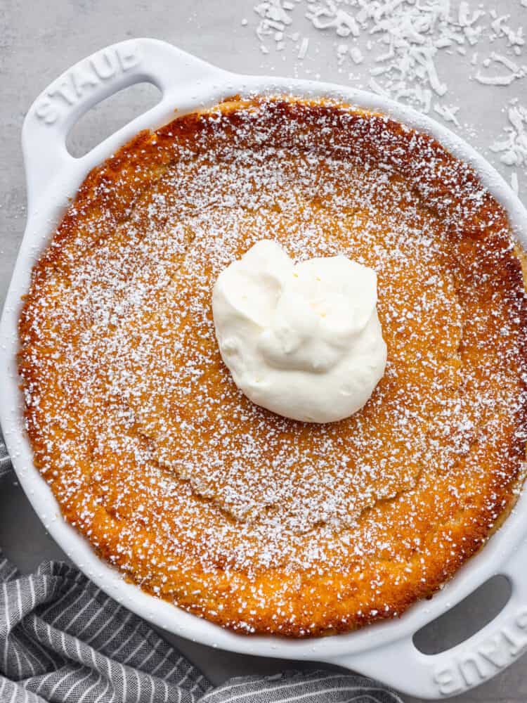 Don't be fooled by the name, this impossible pie is one of the easiest pies you'll ever make! Called "impossible" because it magically forms its own crust, you can have this pie ready for the oven in just 7 minutes. This pie is a classic for a reason- the creamy custard filling and crunchy topping are irresistible! Top-down view of an entire impossible pie, garnished with shredded coconut.