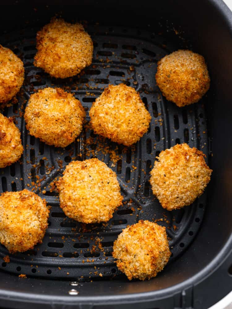 These air fryer mac and cheese balls are crunchy, gooey, and full of delicious cheesy flavor! They are sure to be a hit with your kids or dinner guests, and you'll get this recipe requested again and again. Cooked mac and cheese balls in an air fryer basket.