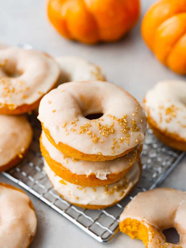 Meet your new favorite fall treat- moist, spiced pumpkin donuts covered in a decadent brown butter glaze! They cook in 15 minutes for a quick and delicious fall breakfast or dessert. With how amazing they are, they'll disappear in no time! Top-down view of 3 donuts stacked on top of each other.
