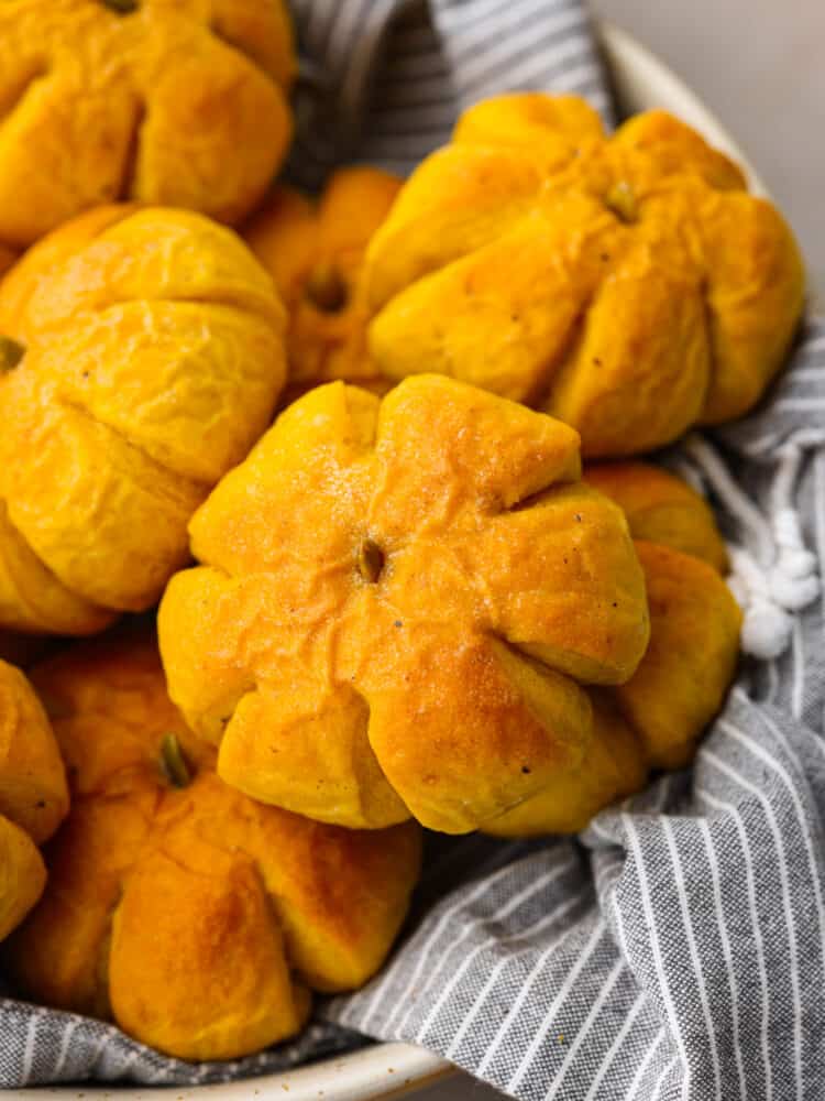 These pumpkin dinner rolls are the perfect, festive side dish to add to any fall meal! They not only taste like pumpkin but they are shaped just like one as well! Impress all of your guests by making these rolls and taking your holiday celebrations to the next level. A closeup of a pumpkin dinner roll.