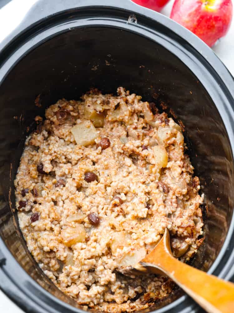 This cinnamon apple oatmeal is easily made in the slow cooker for a creamy, hearty breakfast that everyone will love. It's so nice to wake up in the morning and enjoy a ready-made breakfast filled with steel-cut oats, chopped apples, and raisins! Cooked apple cinnamon oatmeal in a slow cooker.