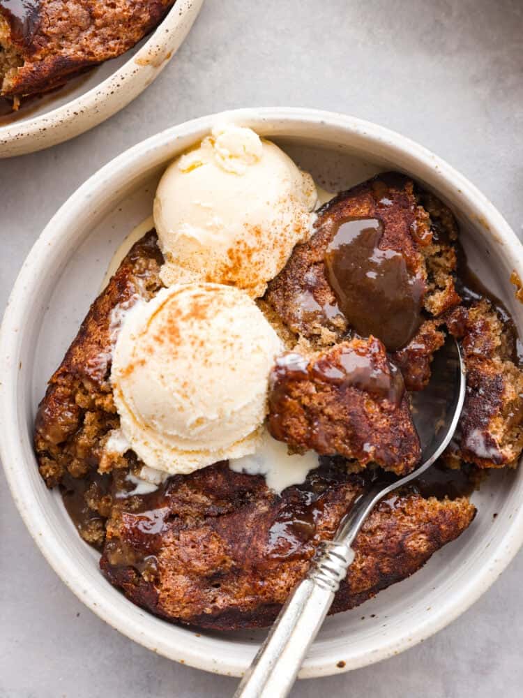Snickerdoodle cobbler is loaded with cinnamon and creates its own caramel sauce while it bakes! It's soft, sweet and so delicious. It makes the perfect fall dessert that all of your guests will be dying to try! The topview of a bowl of snickerdoodle cobbler with 2 scoops of vanilla ice cream on top.