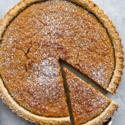 Treacle tart with a slice being lifted out of the tart with a pie scoop.
