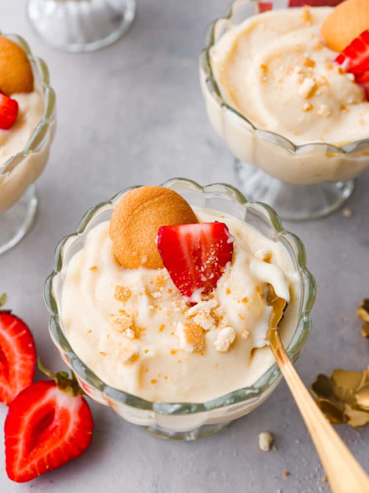 If you're looking for a tried and true vanilla pudding recipe, this is it! This homemade vanilla pudding is perfectly sweet, silky smooth, and really easy to make! Top-down view of vanilla pudding in a glass cup being scooped with a gold spoon.