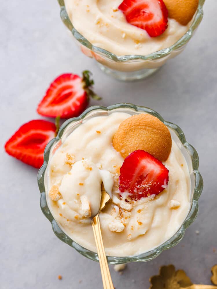 If you're looking for a tried and true vanilla pudding recipe, this is it! This homemade vanilla pudding is perfectly sweet, silky smooth, and really easy to make! Top-down view of vanilla pudding in a glass cup, garnished with a sliced strawberry and Nilla Wafer.